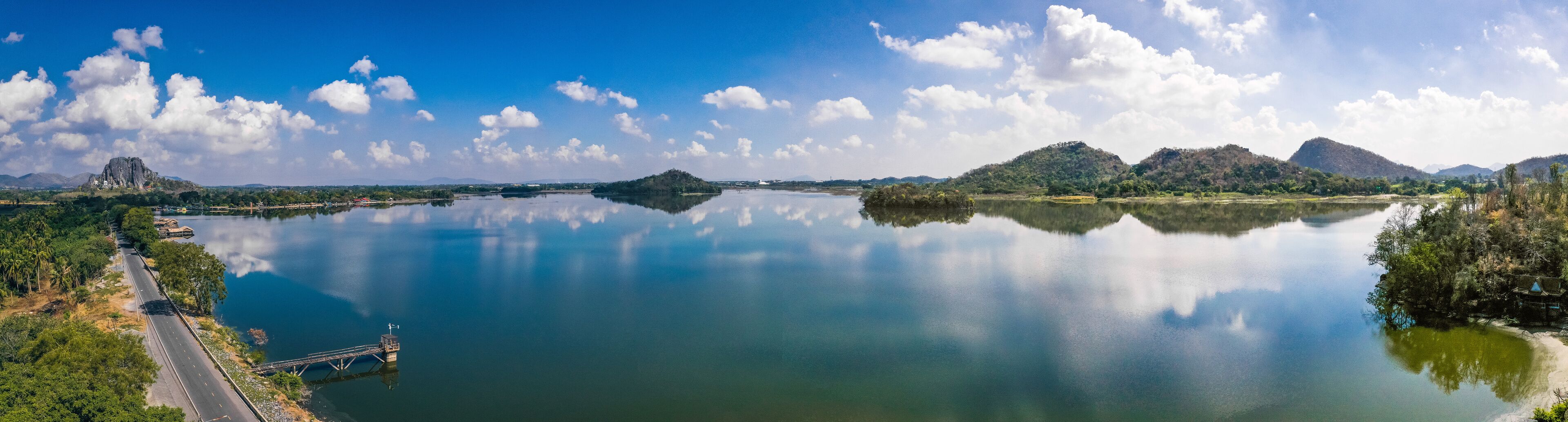 A calm river with a bridge, mountains, and a clear sky.