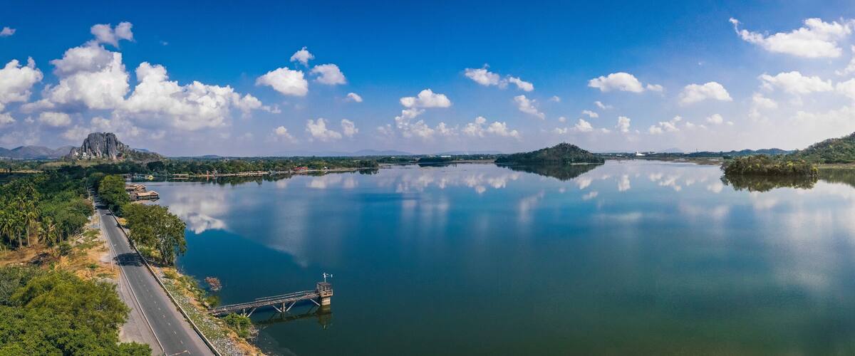 A calm river with a bridge, mountains, and a clear sky.