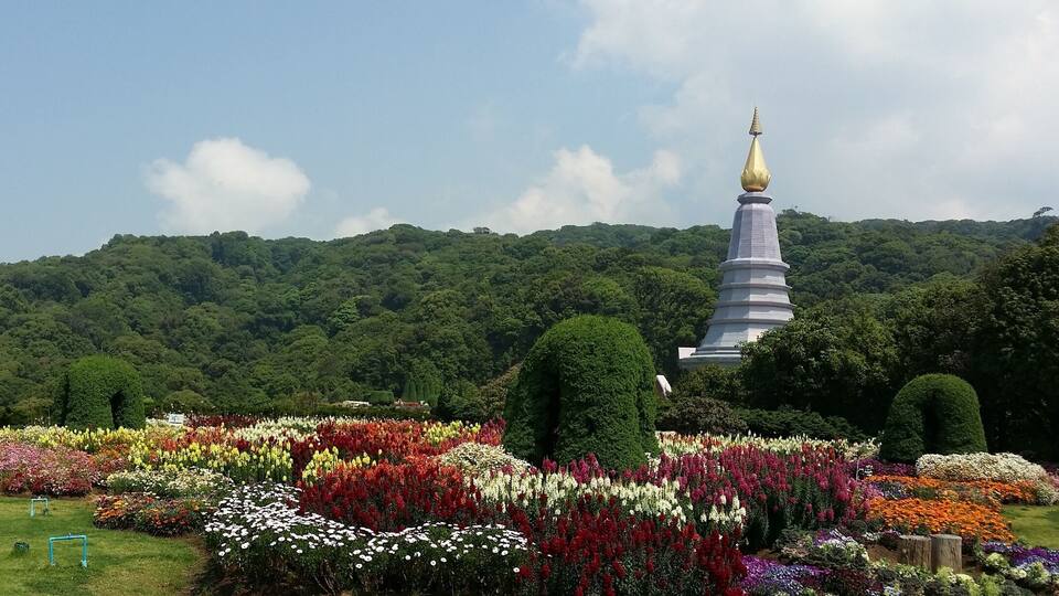 A garden with colorful flowers and a pagoda with a golden spire.