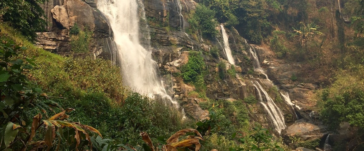 A waterfall cascading down a rocky cliff surrounded by dense greenery.