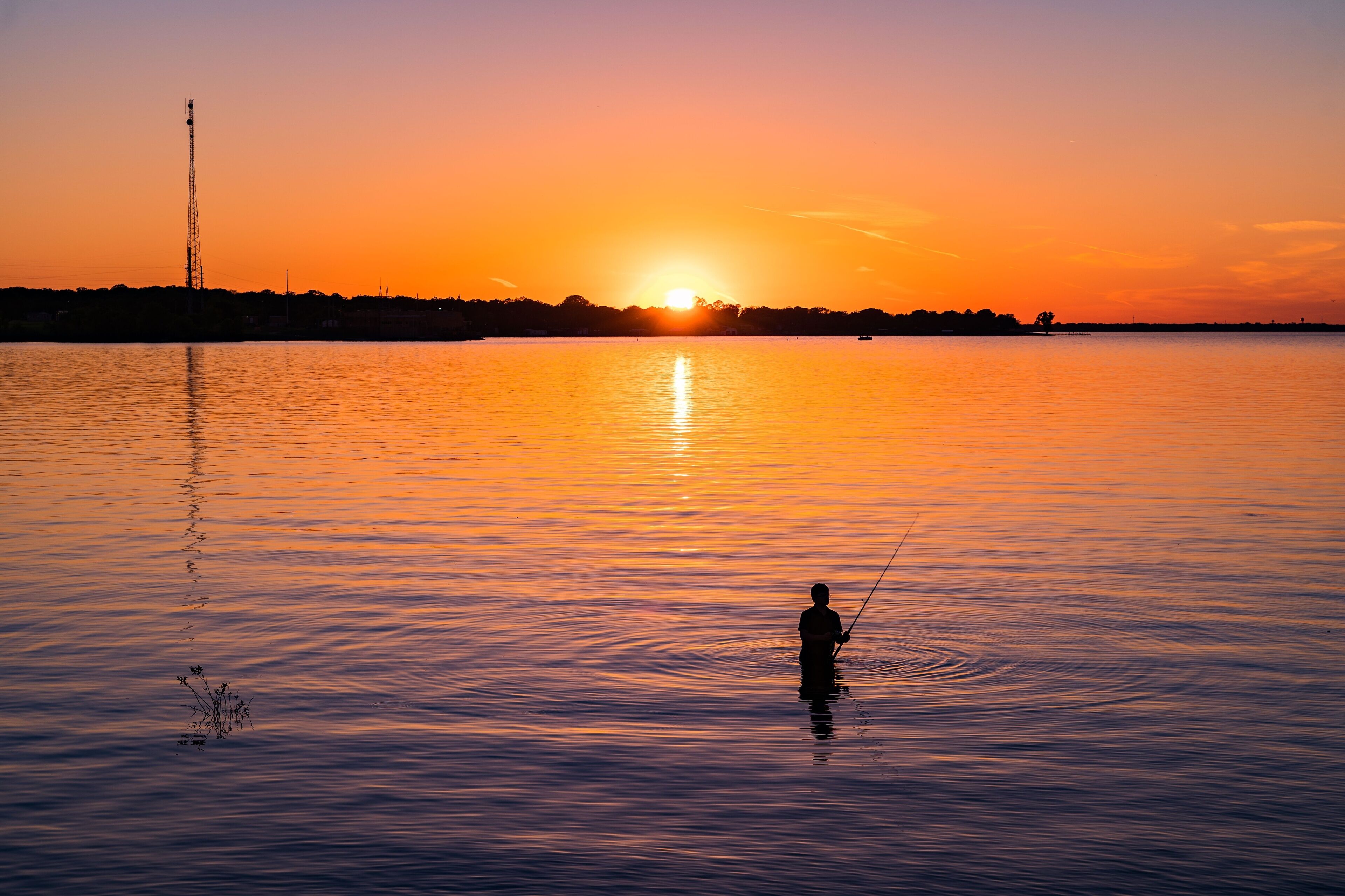 Silhouette of a man fishing at sunset at Lake Tawakoni State Park, Texas