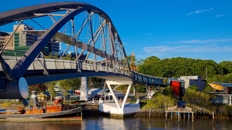 Un puente de acero grande sobre un río, con una barca amarrada debajo.