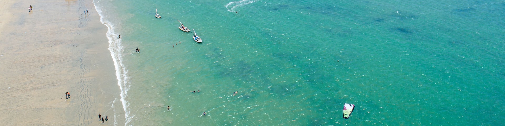 A beach with clear turquoise waters, a sandy shore, and several boats.