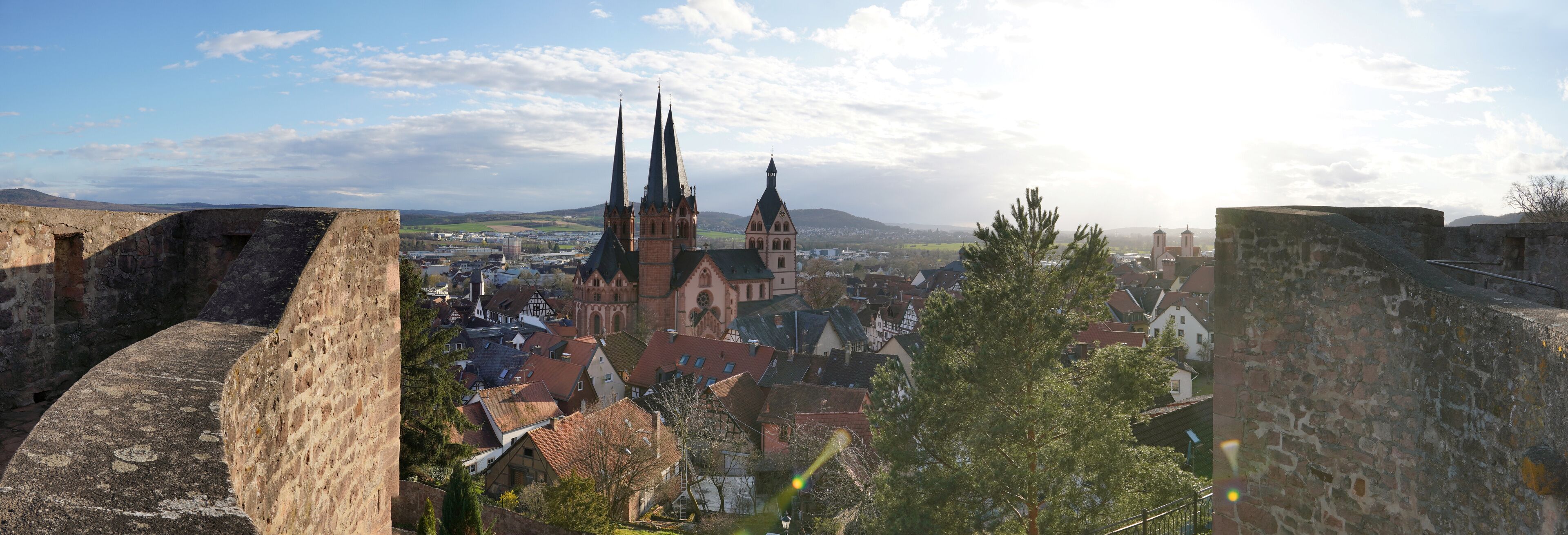 A historic town with medieval architecture, including a church with tall spires and a castle wall.