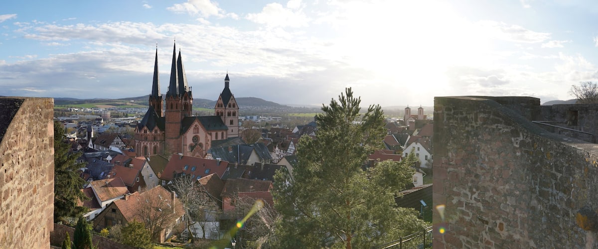 A historic town with medieval architecture, including a church with tall spires and a castle wall.