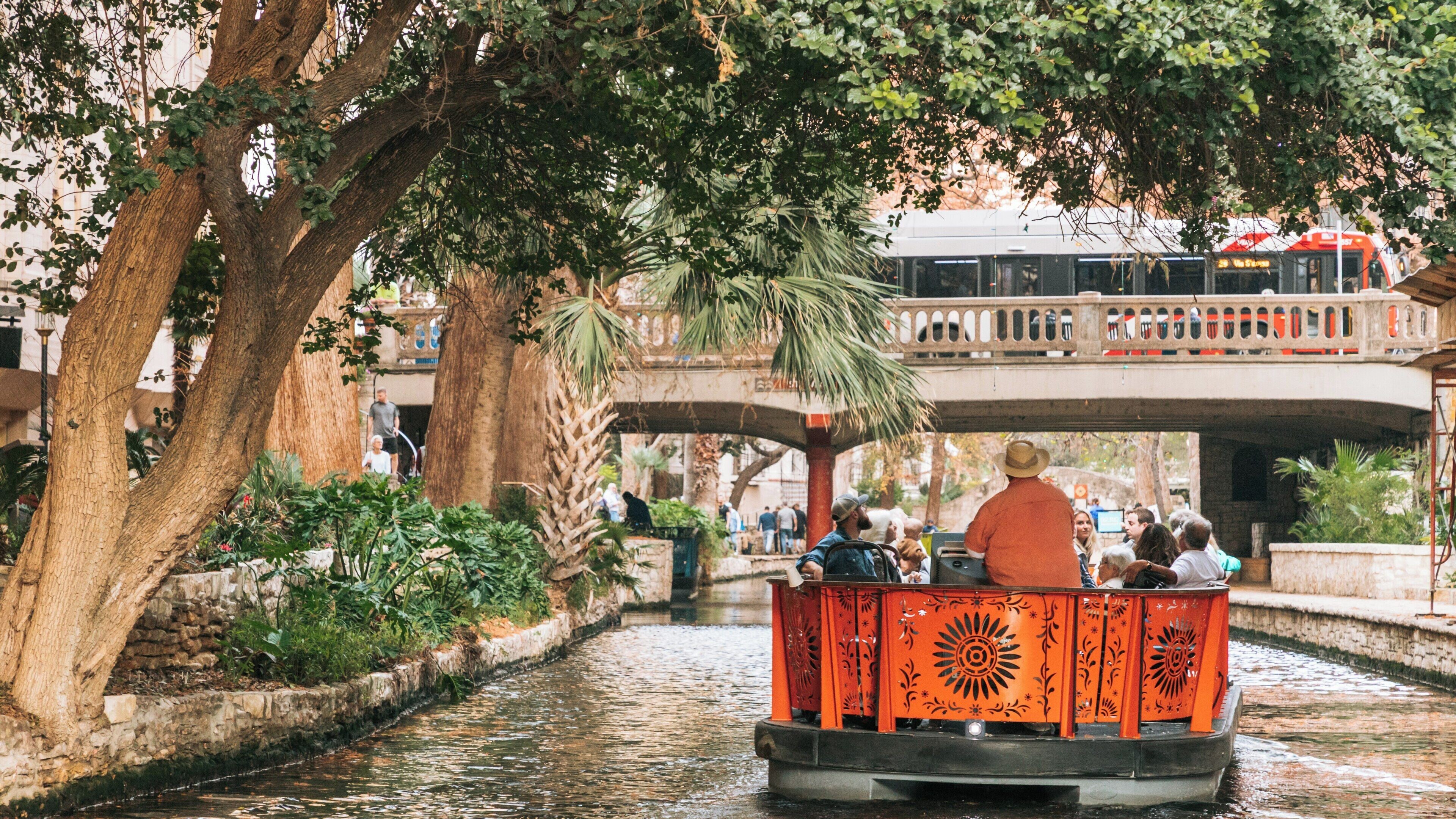 Explore the beauty of River Walk in Downtown San Antonio, Texas as visitors enjoy a serene boat ride through lush greenery