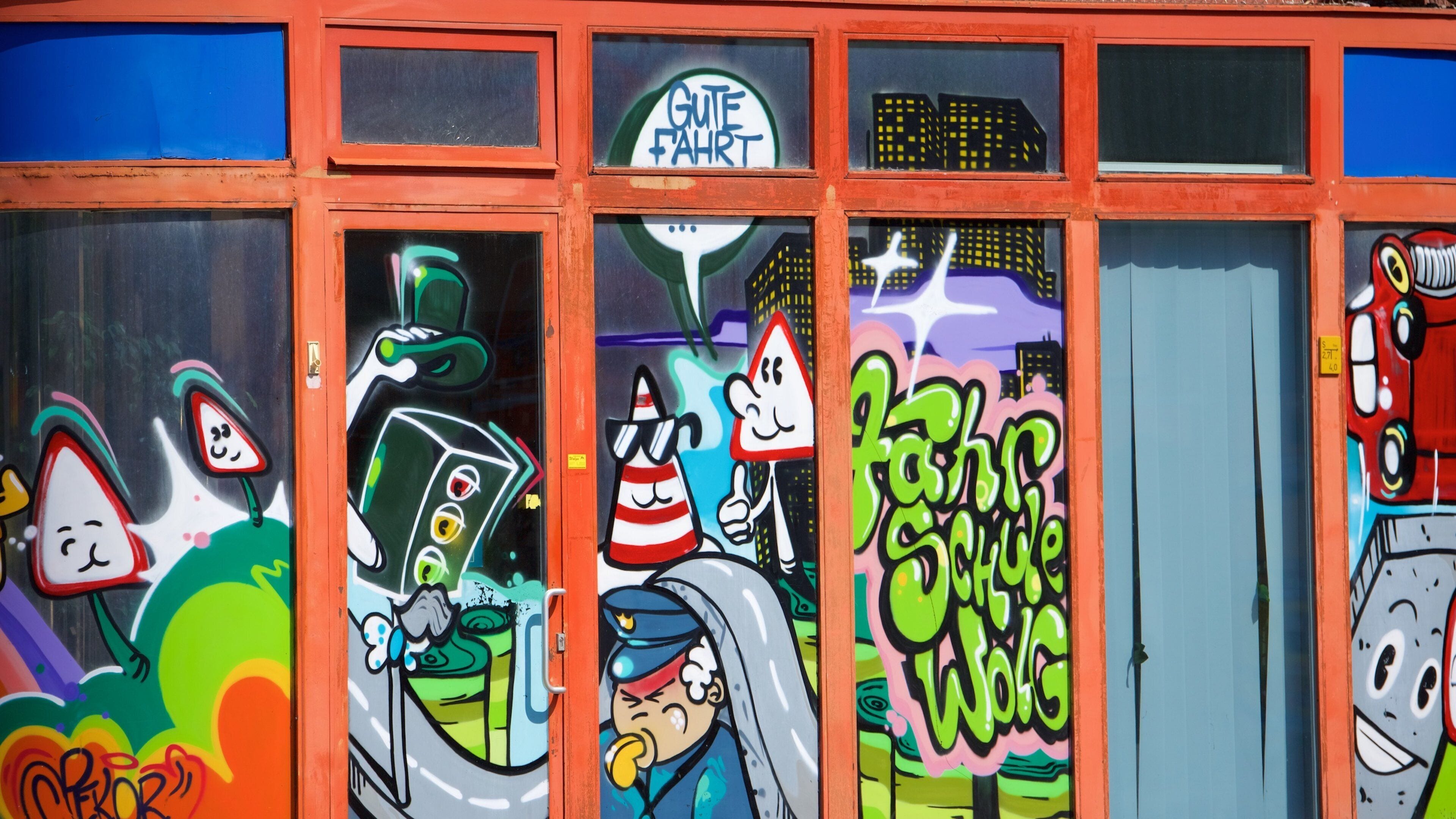 Des graffitis colorés sur les fenêtres d’un immeuble.