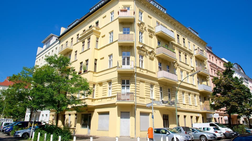 A yellow multi-story building with balconies and a street in front.