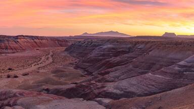 A canyon with layered rock formations and a sunset.