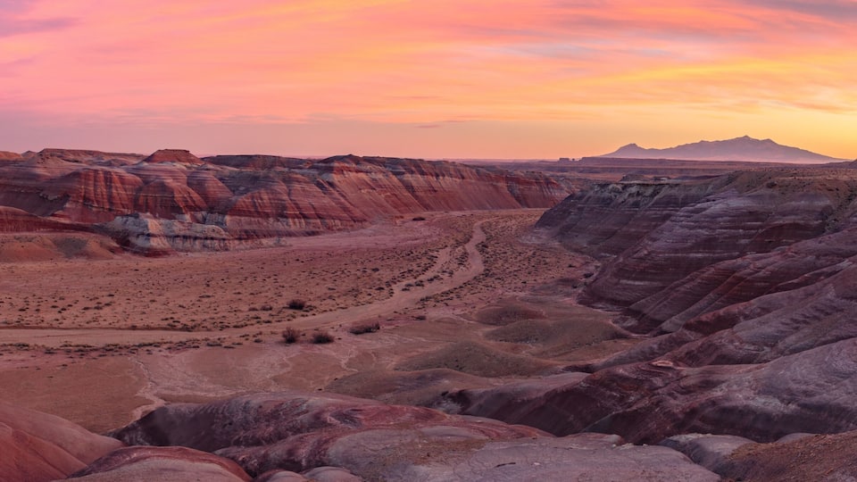A canyon with layered rock formations and a sunset.