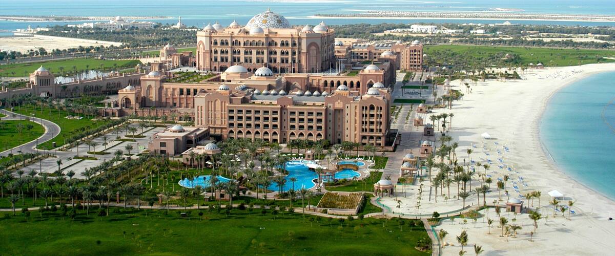 A large resort with multiple domed buildings, a beach, and a pool area.