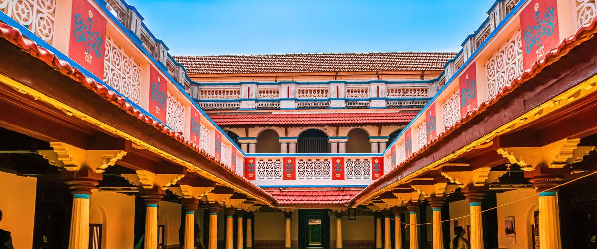 A courtyard with ornate pillars and a tiled roof.
