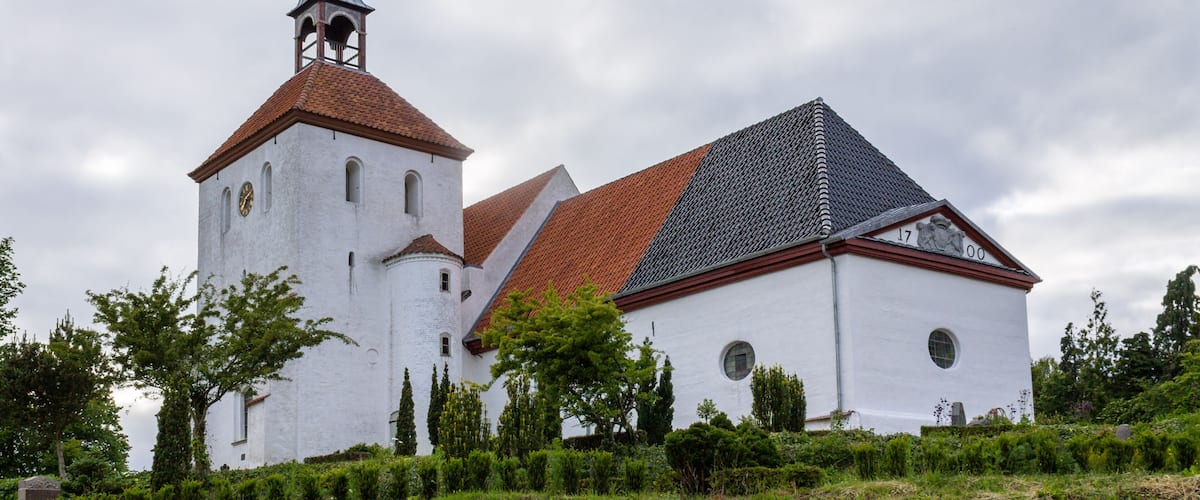 A church with a white facade, a red-tiled roof, and a spire.