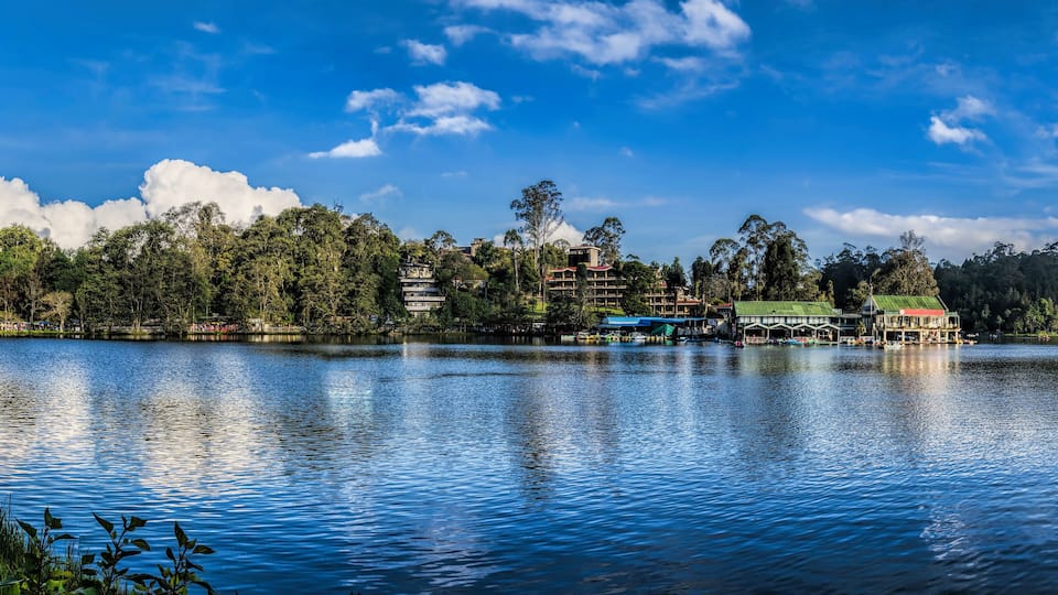 A calm lake with buildings and trees in the background.