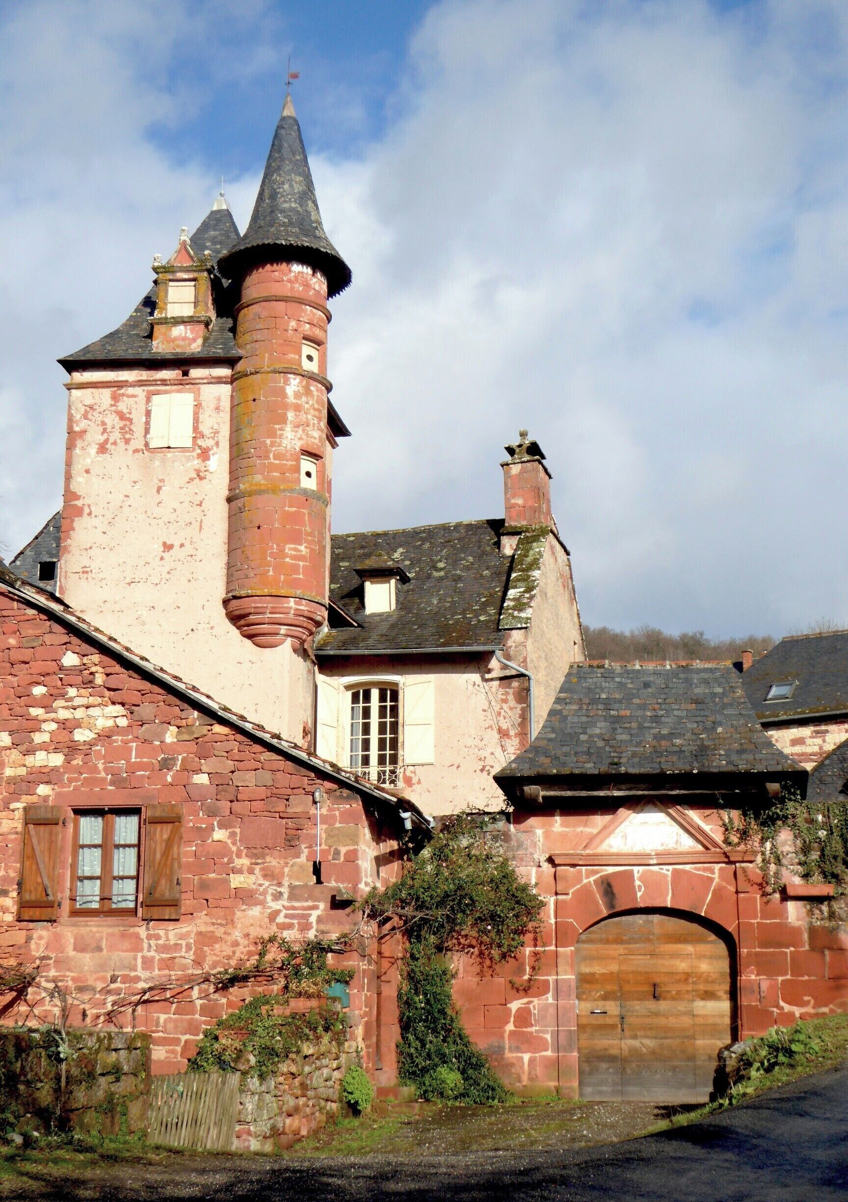 A historic stone building with a tower, arched entrance, and a wooden door.