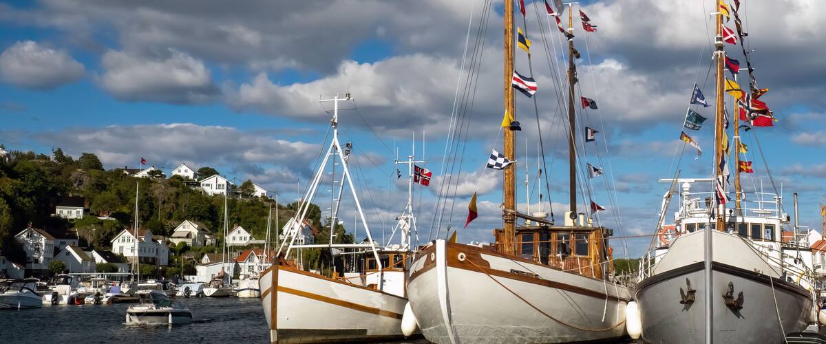 Tall ships in the old harbor of the historical seaside resort town of Risør on the southern coast of Norway.