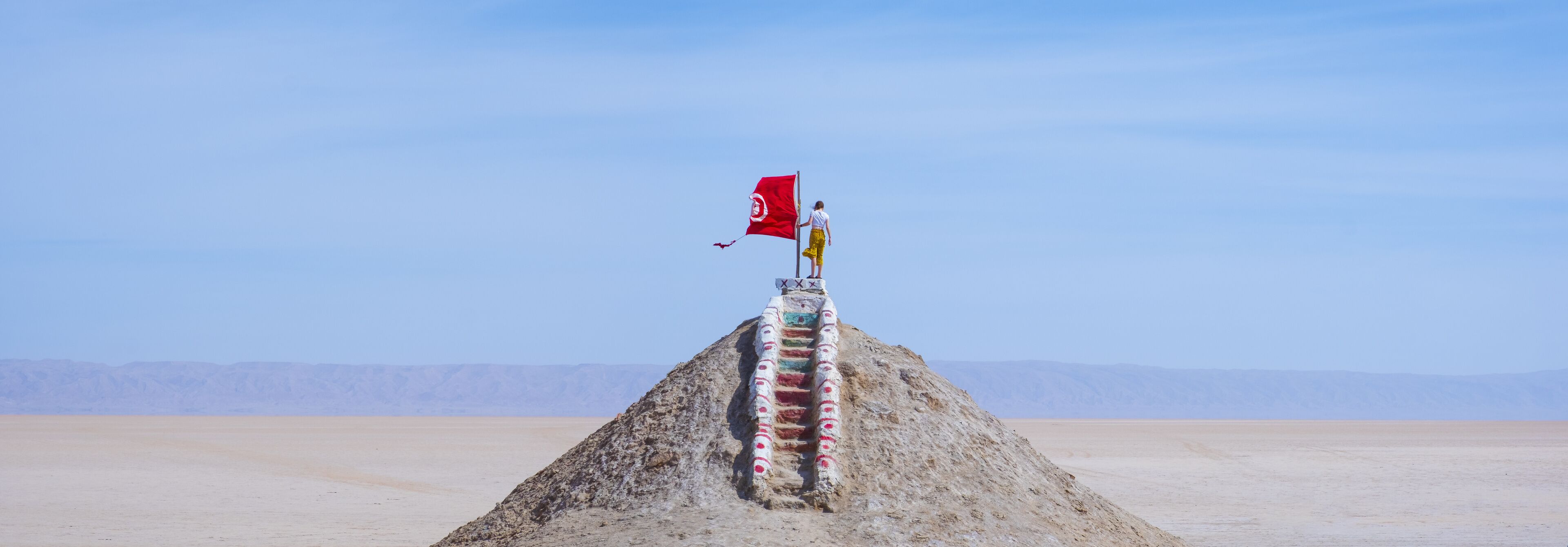 A flagpole with a red flag in a desert landscape.