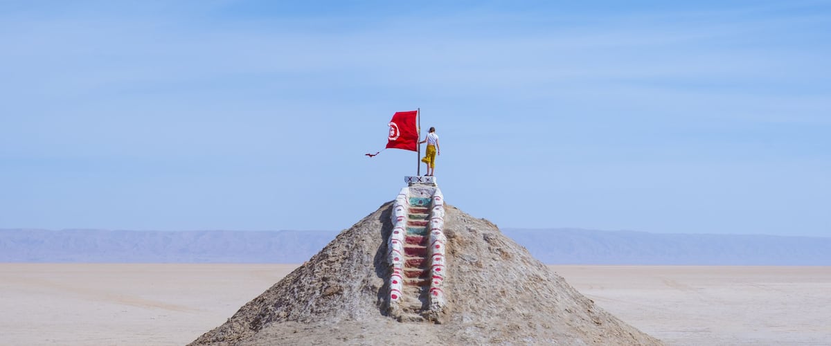 A flagpole with a red flag in a desert landscape.
