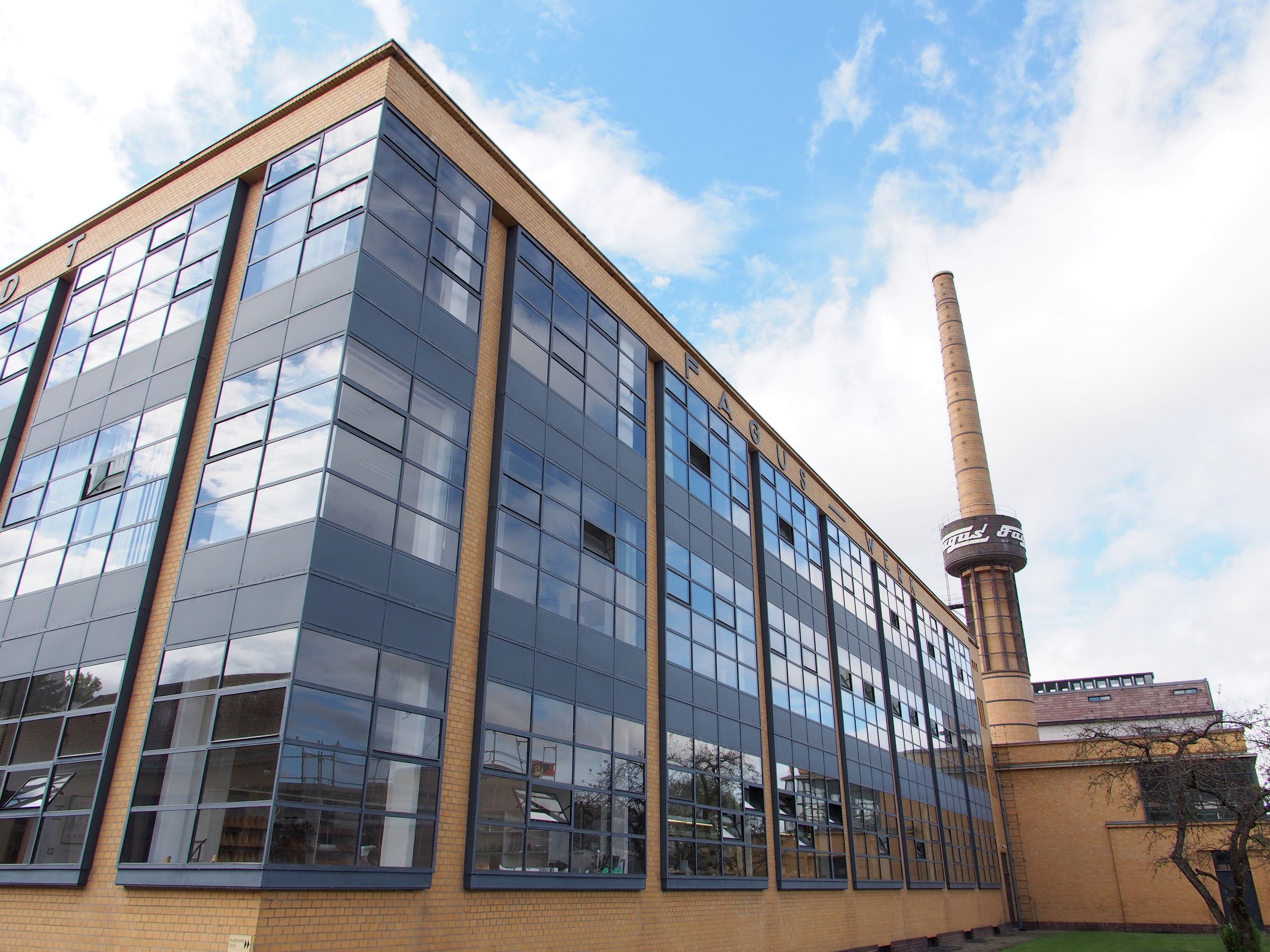 Moderni rakennus, jossa on suuret, heijastavat ikkunat ja korkea savupiippu.