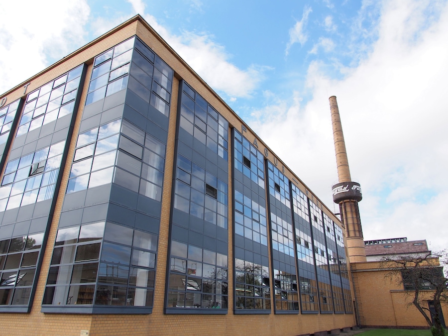A modern building with large reflective windows and a tall chimney.