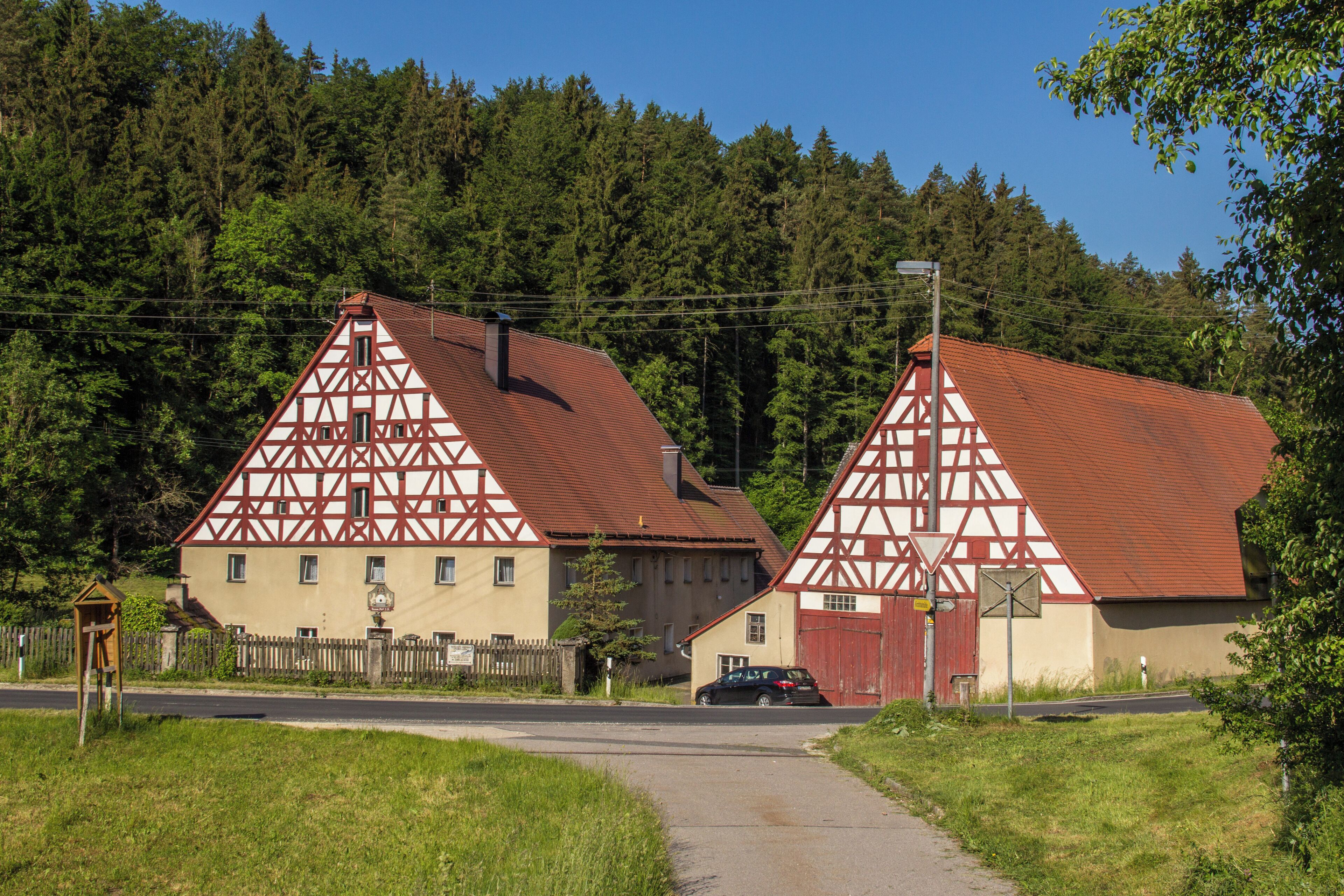 A rural German village with traditional half-timbered houses and a road leading to them.