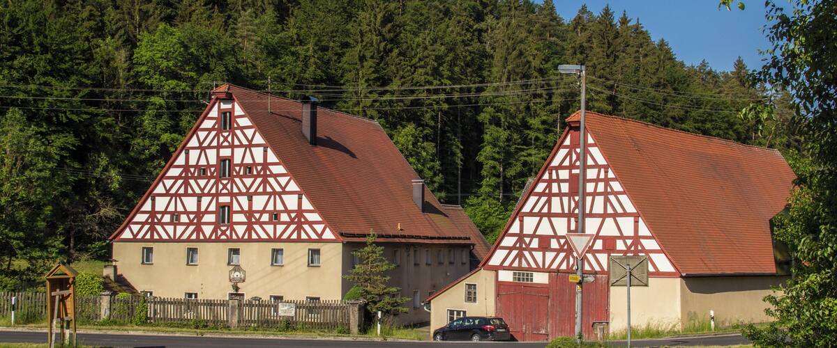 A rural German village with traditional half-timbered houses and a road leading to them.