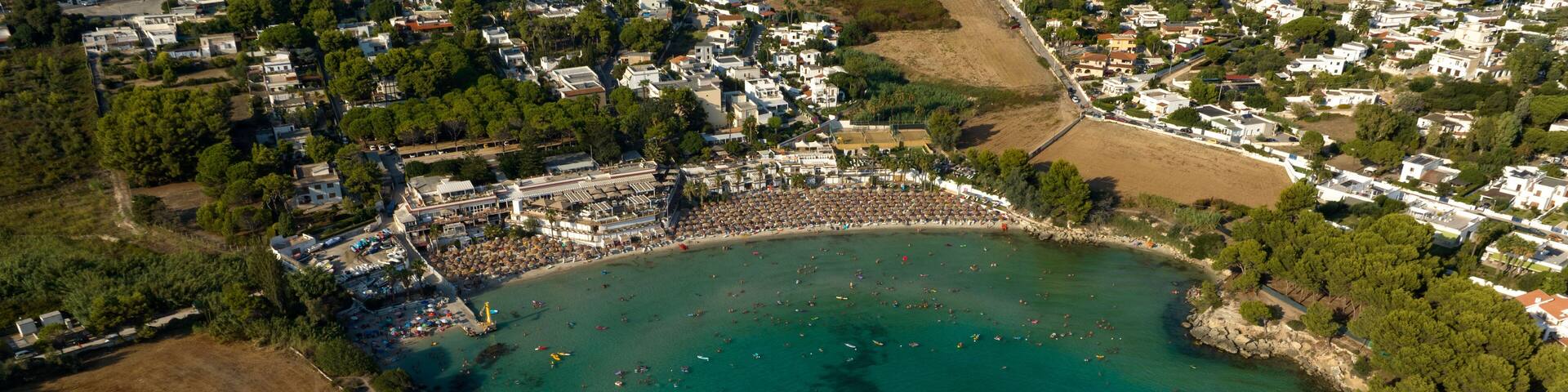 Aerial view of the beach of Lido Gandoli in the municipality of Leporano, near Taranto, in Puglia, Italy. There are many people under the umbrellas and in the sea.