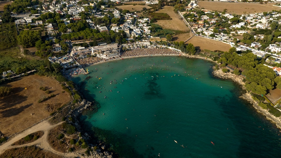 Aerial view of the beach of Lido Gandoli in the municipality of Leporano, near Taranto, in Puglia, Italy. There are many people under the umbrellas and in the sea.