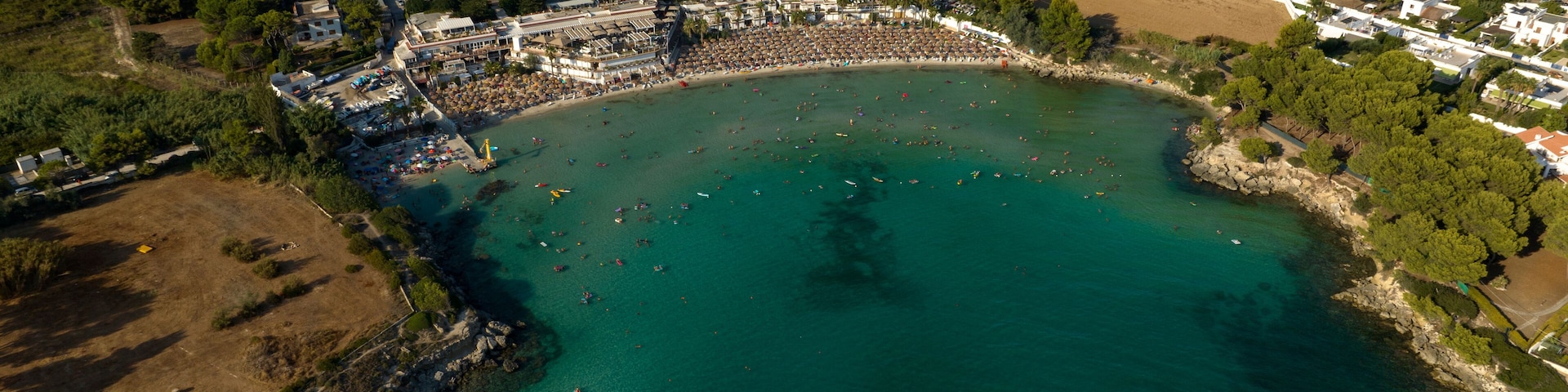 Aerial view of the beach of Lido Gandoli in the municipality of Leporano, near Taranto, in Puglia, Italy. There are many people under the umbrellas and in the sea.