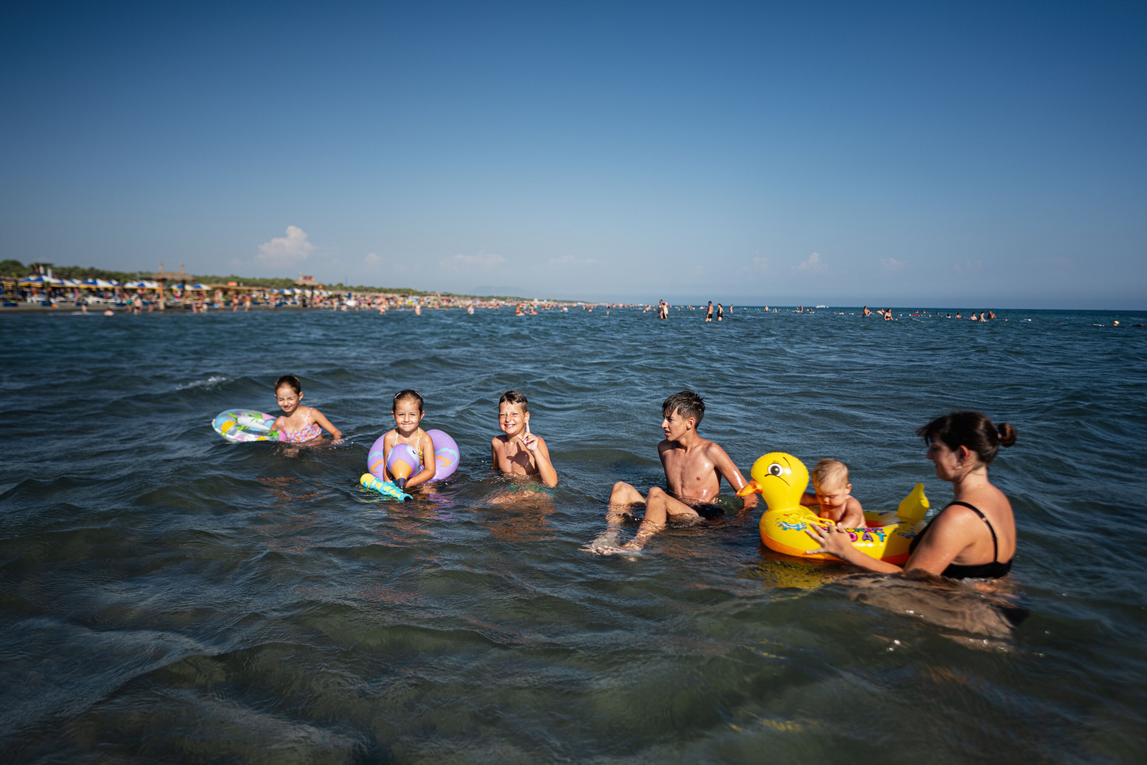 Happy family and children enjoying a fun day at a crowded beach in Ulcinj, Montenegro.