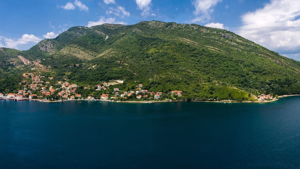 Aerial panoramic beautiful view from above to Kotor Bay and regular passenger ferry from Lepetane to Kamenari by a sunny afternoon