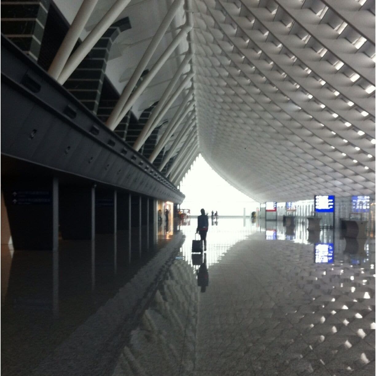 Interior arquitectónico moderno con piso reflectante y una persona caminando.