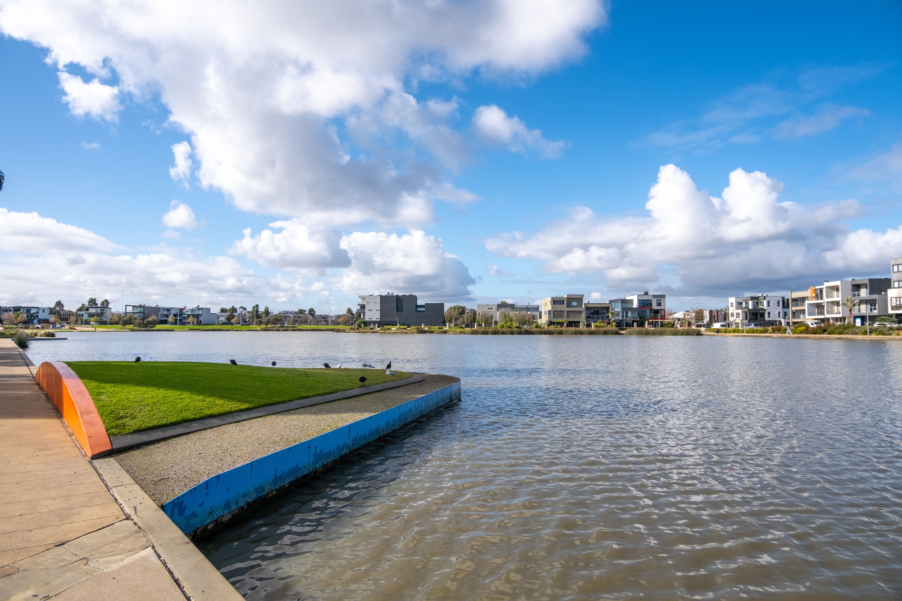 Urban waterfront view of Caroline Springs Lake with some modern and new residential suburban houses in the distance. Melbourne VIC Australia