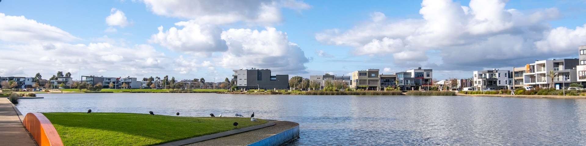 Urban waterfront view of Caroline Springs Lake with some modern and new residential suburban houses in the distance. Melbourne VIC Australia