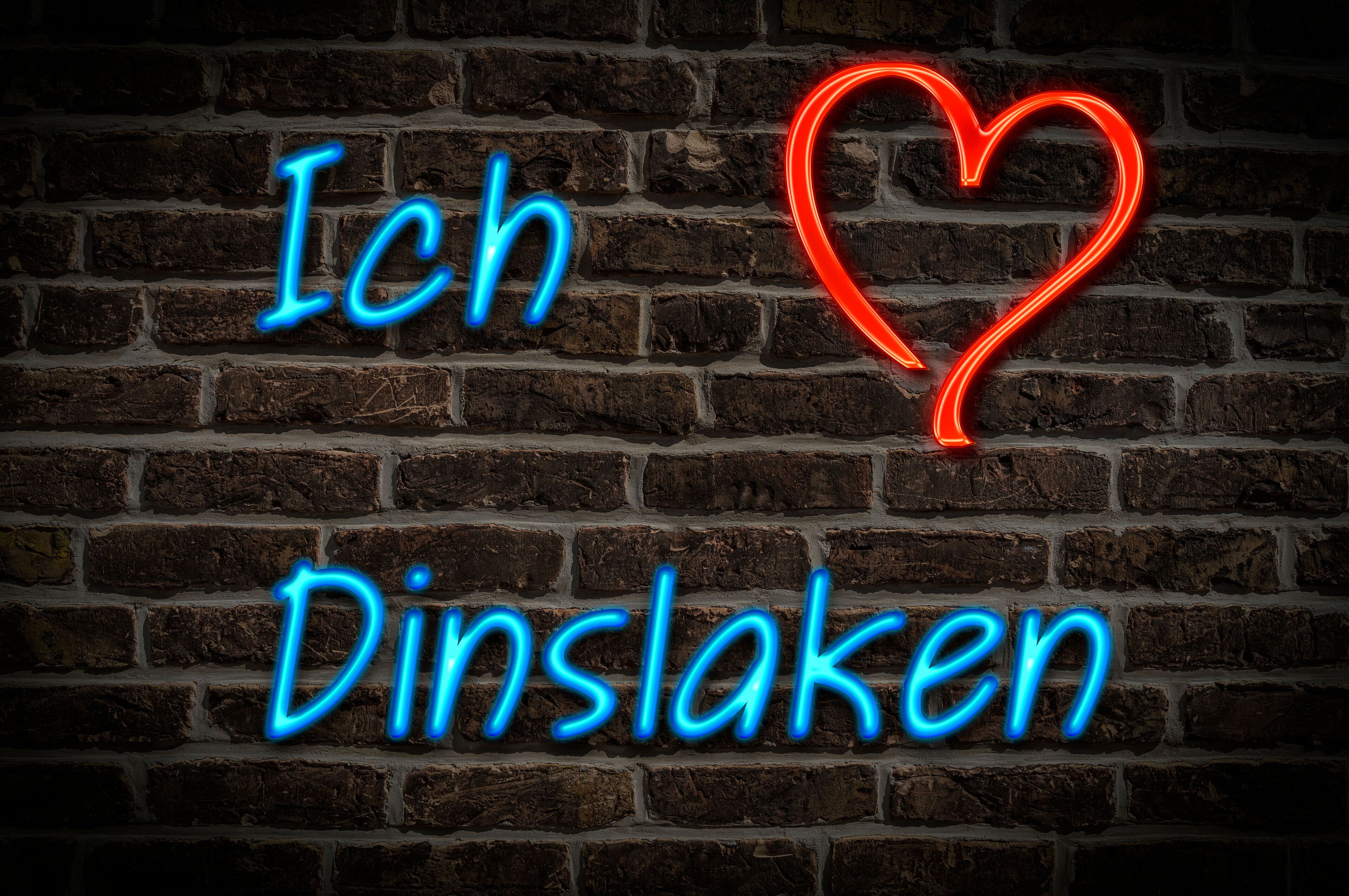 A neon sign with the text "Ich Dinslagen" and a heart symbol on a brick wall.