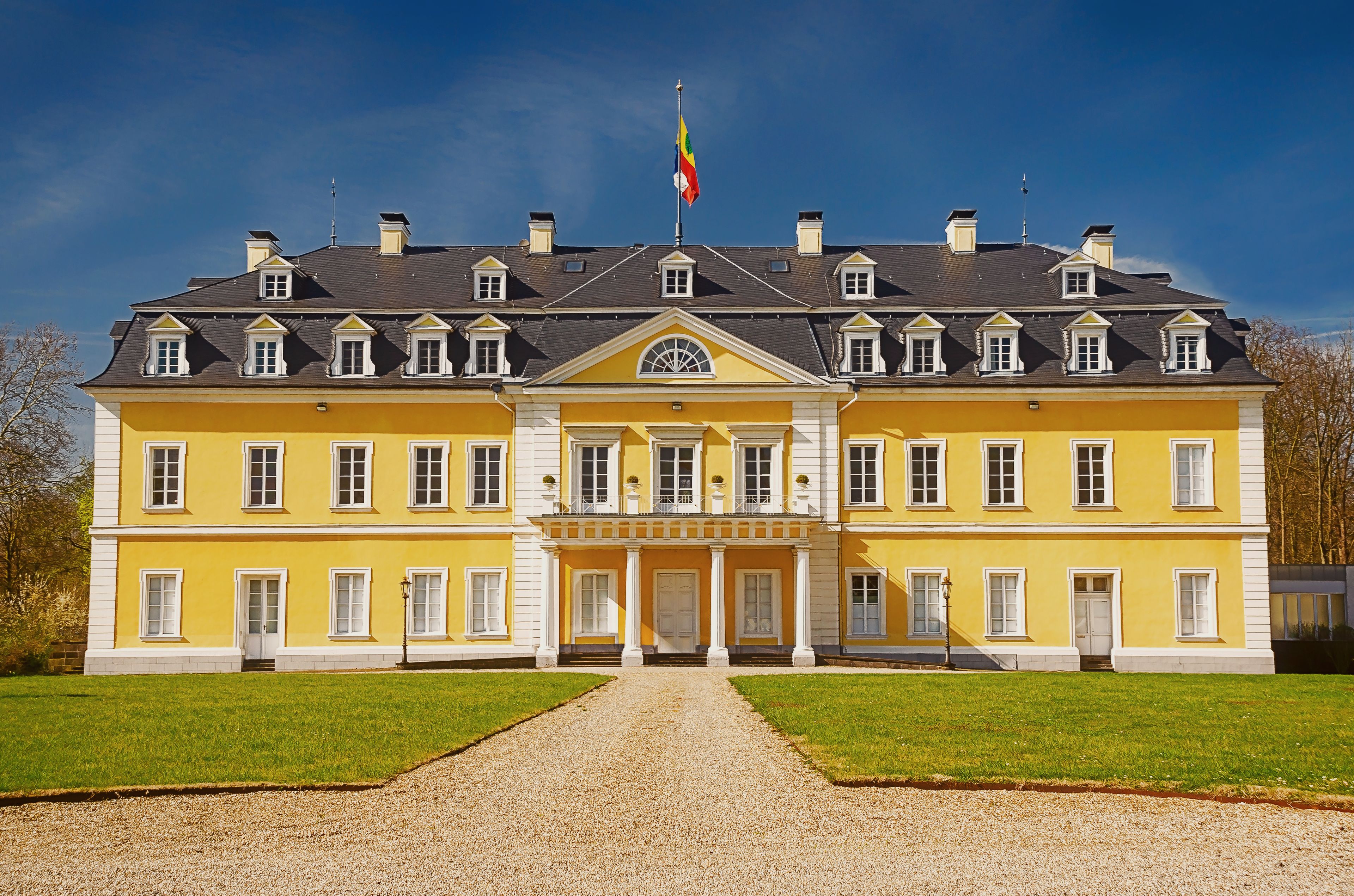 A large yellow building with a symmetrical facade, multiple windows, and a central entrance with columns.