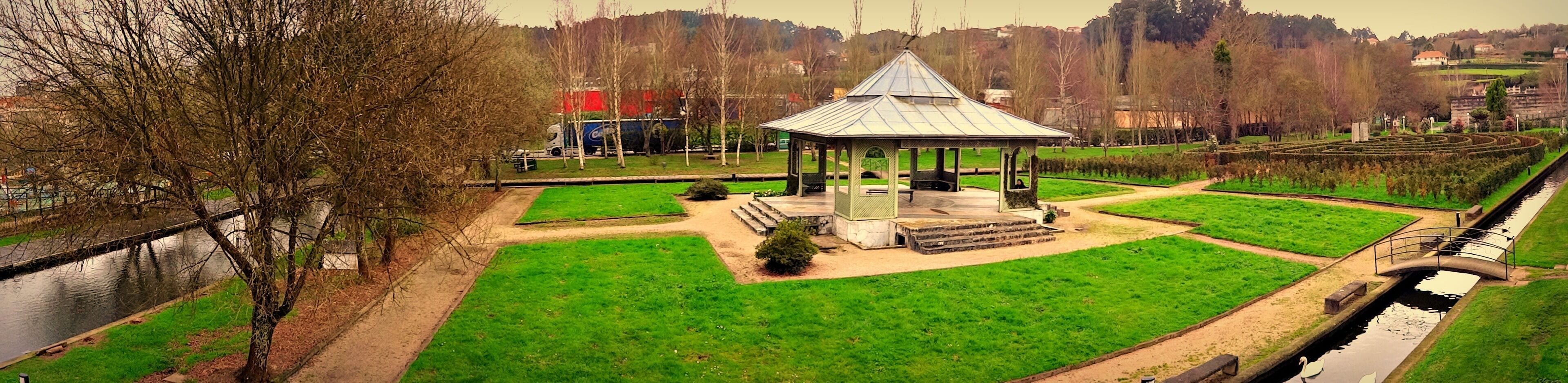 Un parque con un pabellón, un canal y un césped bien cuidado.