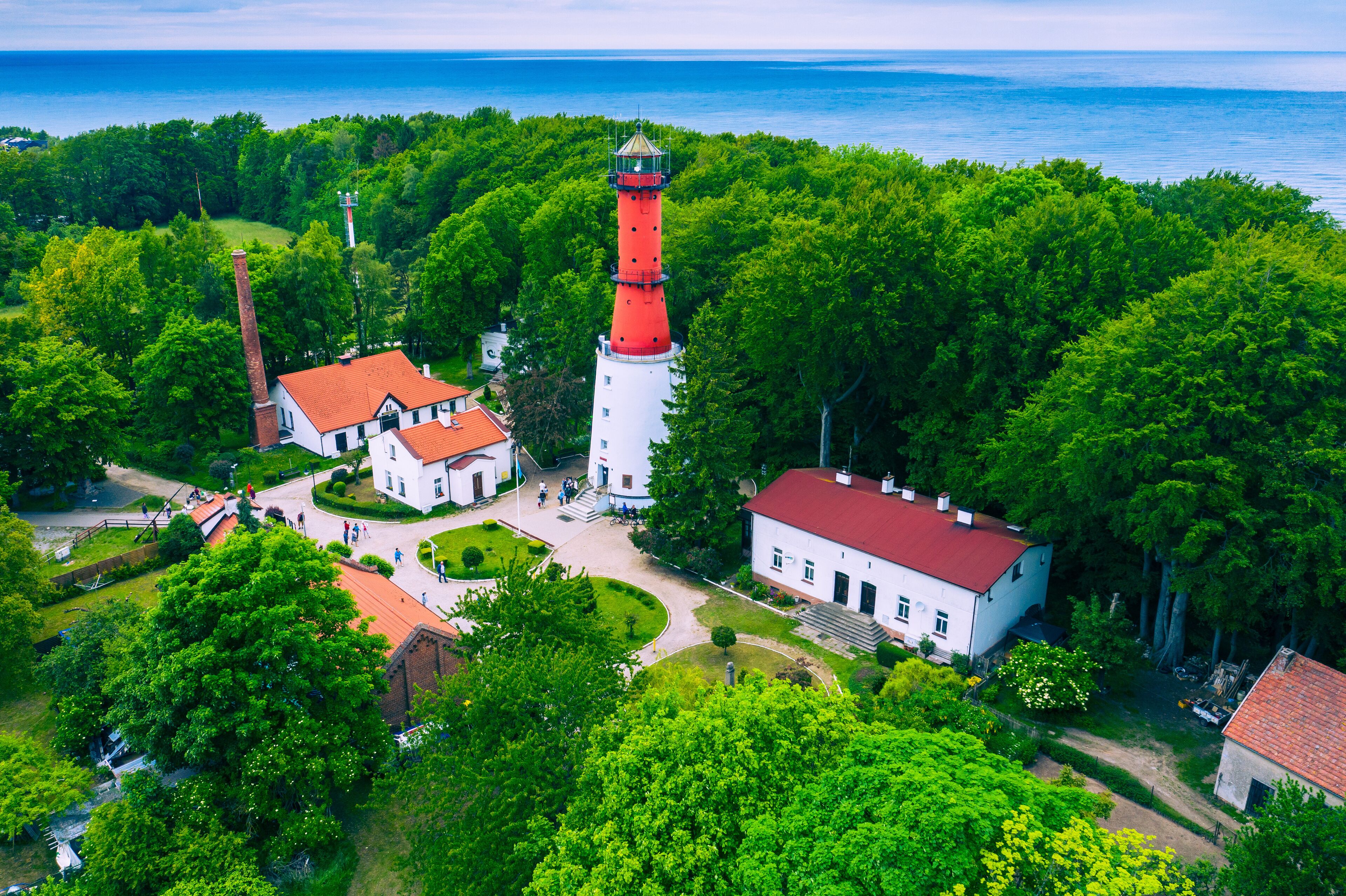 A lighthouse surrounded by lush greenery and a coastal view.