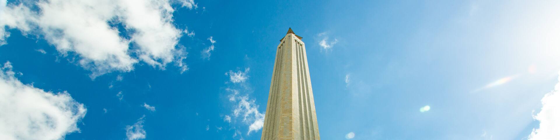 A tall, narrow tower against a blue sky with scattered clouds.