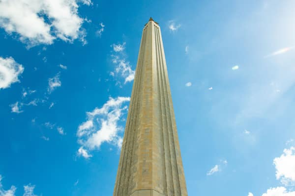 A tall, narrow tower against a blue sky with scattered clouds.