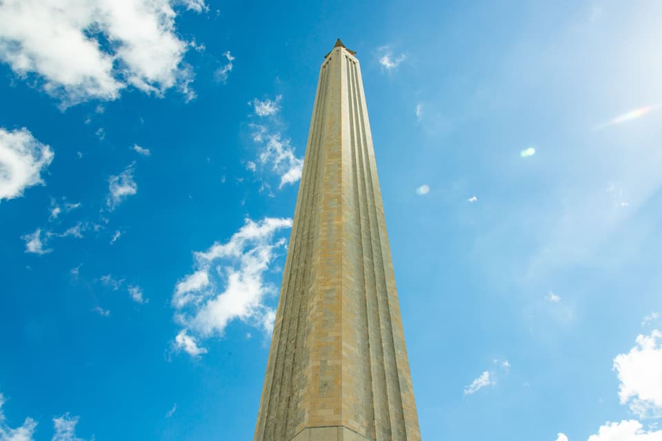 A tall, narrow tower against a blue sky with scattered clouds.