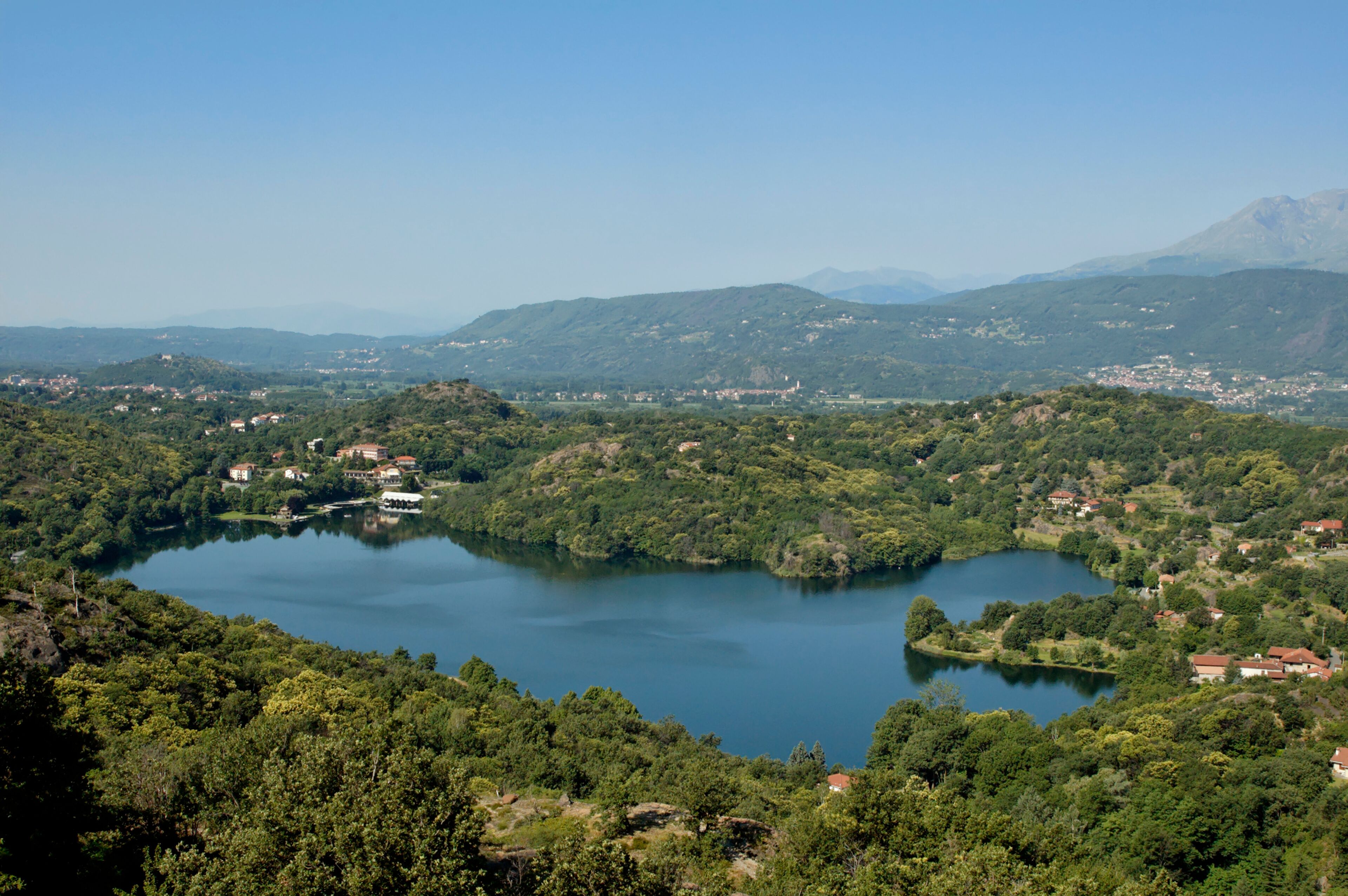 A lake surrounded by lush green hills and scattered houses.