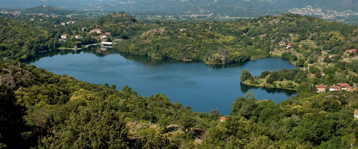 A lake surrounded by lush green hills and scattered houses.