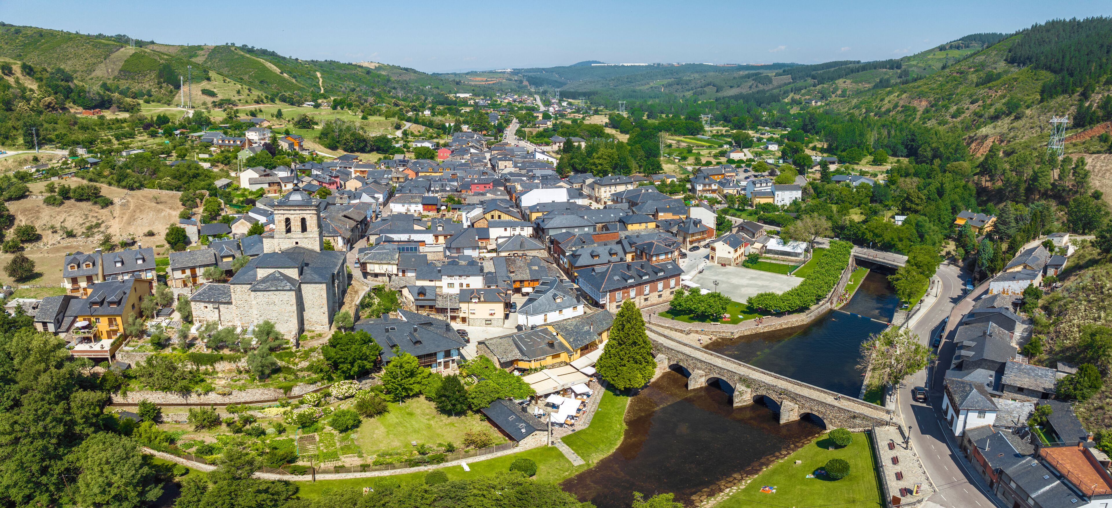 A town with a river, a bridge, and surrounding hills.