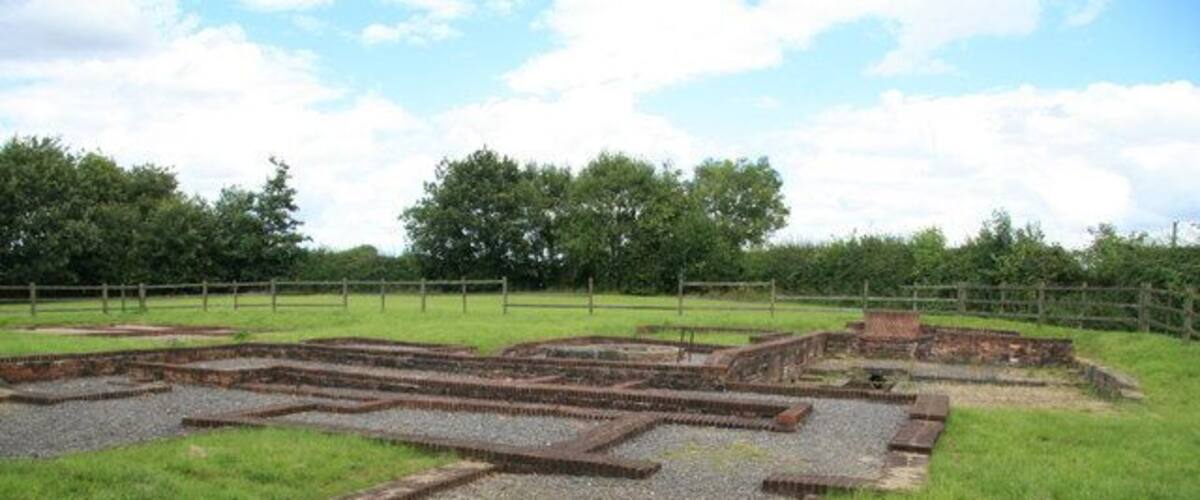 An archaeological site with ancient brick structures and gravel paths.