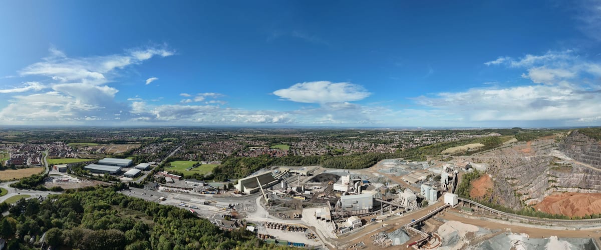 Aerial drone view of heavy industrial aggregates quarry mining site, heavy plant machinery, warehouses, diggers, buildings near Coalville Leicester UK