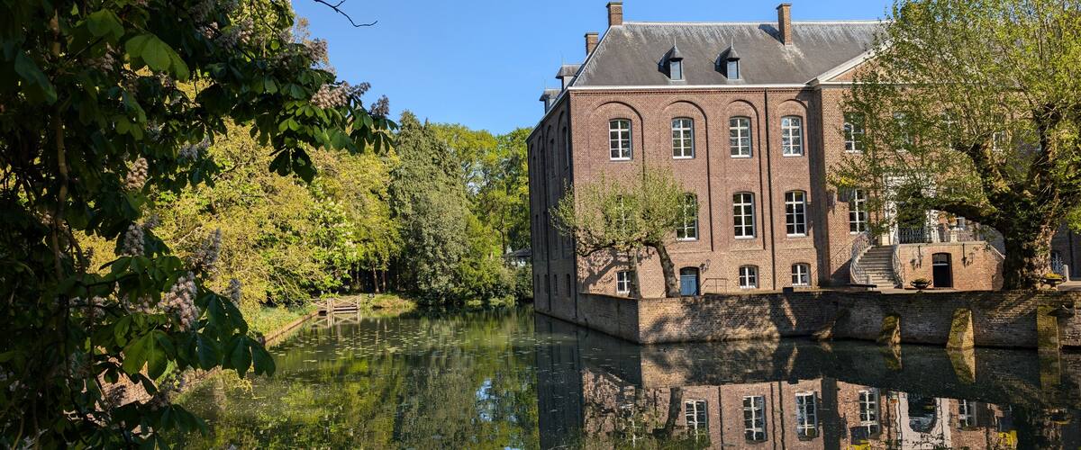 A historic brick building with arched windows and a reflection in the water.