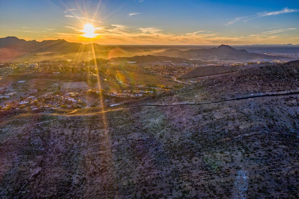 Atardecer sobre un paisaje montañoso con un pueblo en la falda.