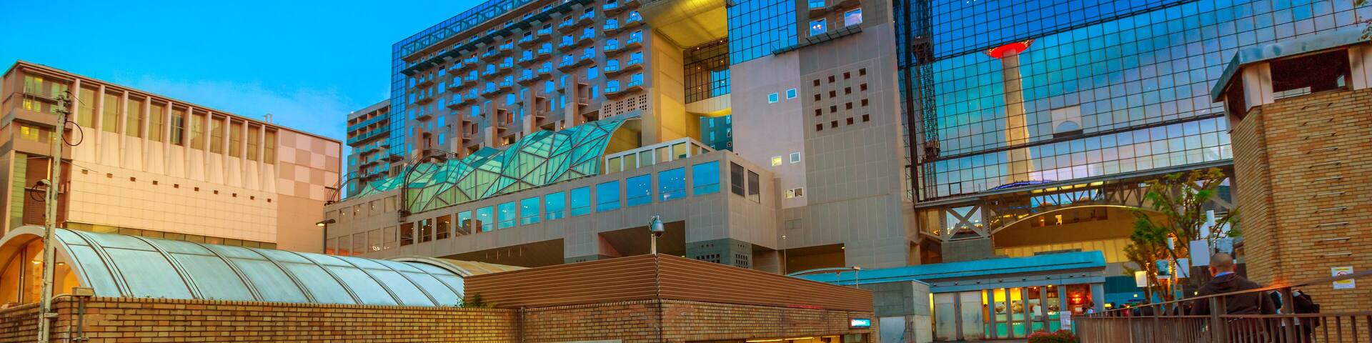 Wide view of Kyoto Tower reflects on glass facade of Kyoto Station building from Karasuma side. Kyoto Station is a major railway station and transportation hub in Kyoto, Japan. Spring season.
