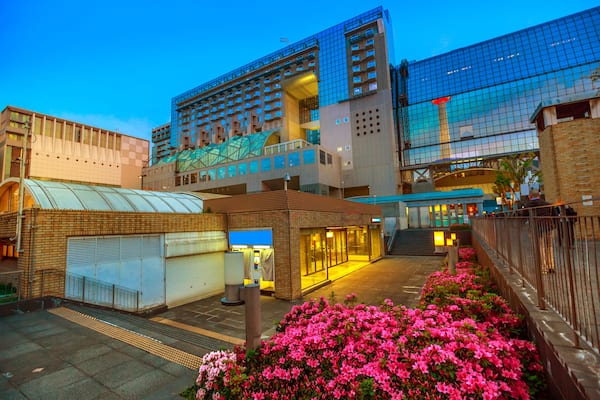 Wide view of Kyoto Tower reflects on glass facade of Kyoto Station building from Karasuma side. Kyoto Station is a major railway station and transportation hub in Kyoto, Japan. Spring season.
